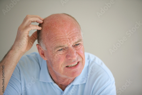 Photo: Senior bald man scratching his head Senior bald man scratching his head