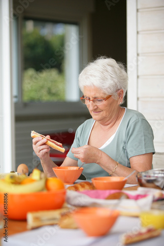 Photo: Senior woman eating on her terrace Senior woman eating on her terrace