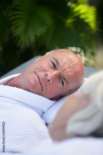 Photo: Senior man relaxing poolside Senior man relaxing poolside