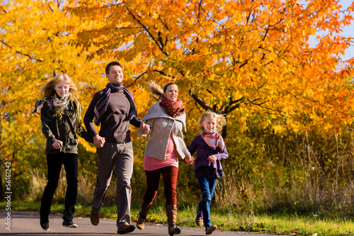 Photo: Family having walk in front of colorful trees in autumn Family having walk in front of colorful trees in autumn