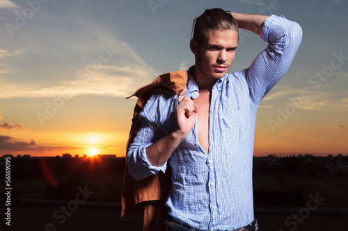 Photo: casual man with hand through hairwith sunset behind casual man with hand through hairwith sunset behind