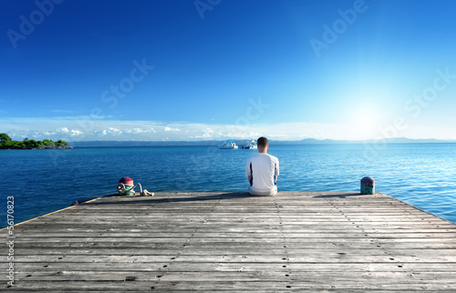 Photo: young man relax siting on pier young man relax siting on pier