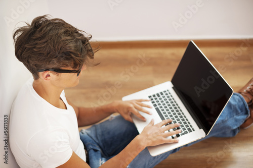 Photo: Young man looking thoughtful and using laptop Young man looking thoughtful and using laptop
