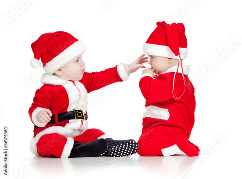 Photo: two funny small kids in Santa Claus clothes isolated on white ba two funny small kids in Santa Claus clothes isolated on white ba