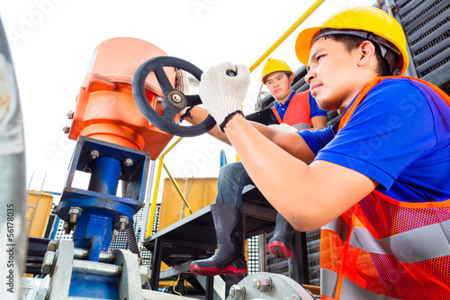 Photo: Technicians working on valve in factory or utility Technicians working on valve in factory or utility