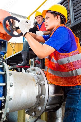 Photo: Technicians working on valve in factory or utility Technicians working on valve in factory or utility