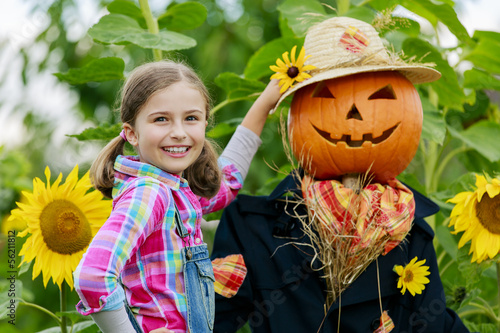Photo: Scarecrow and happy girl in the garden Scarecrow and happy girl in the garden