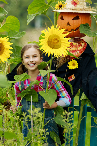 Photo: Scarecrow and happy girl in the garden Scarecrow and happy girl in the garden