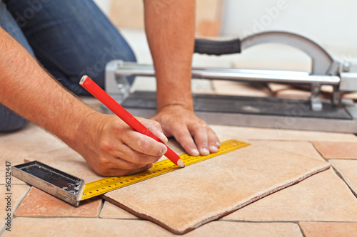 Photo: Laying ceramic floor tiles - man hands closeup Laying ceramic floor tiles - man hands closeup