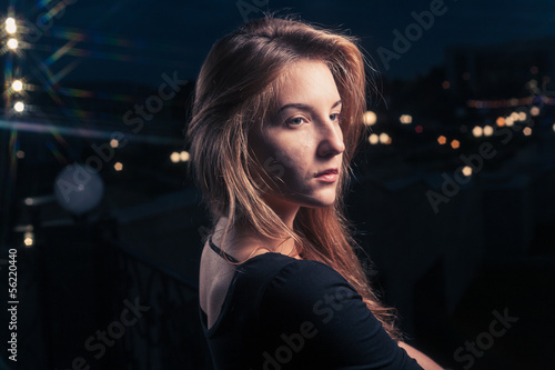 Photo: Beautiful lonely woman in the old house against city night Beautiful lonely woman in the old house against city night