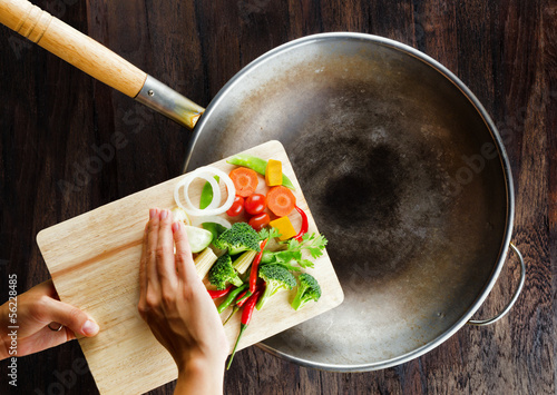 Photo: Fresh vegetables on the cutting board are falling in the wok. Co Fresh vegetables on the cutting board are falling in the wok. Co