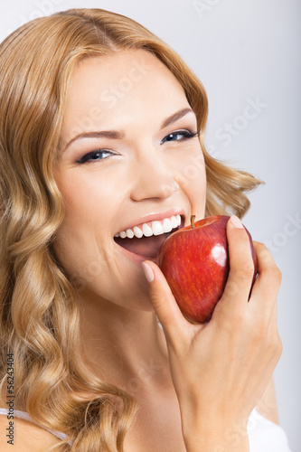 Photo: Woman eating apple, on grey Woman eating apple, on grey