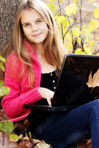Photo: Pretty girl in autumn park with laptop Pretty girl in autumn park with laptop