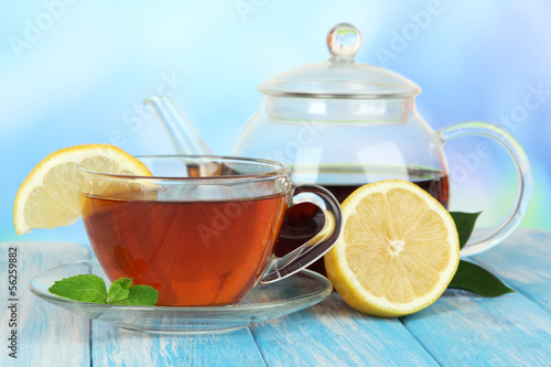Photo: Cup of tea with lemon on table on blue background Cup of tea with lemon on table on blue background