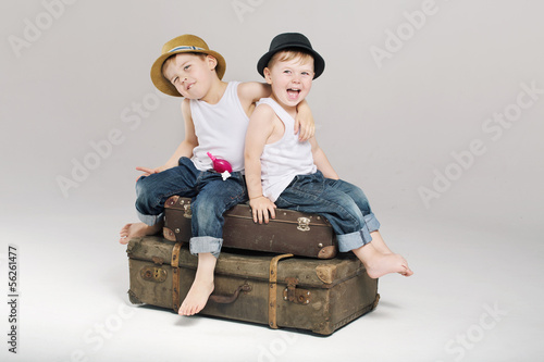 Photo: Two small brothers sitting on the suitcases Two small brothers sitting on the suitcases