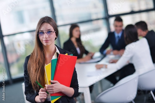 Photo: business woman with her staff in background at office business woman with her staff in background at office