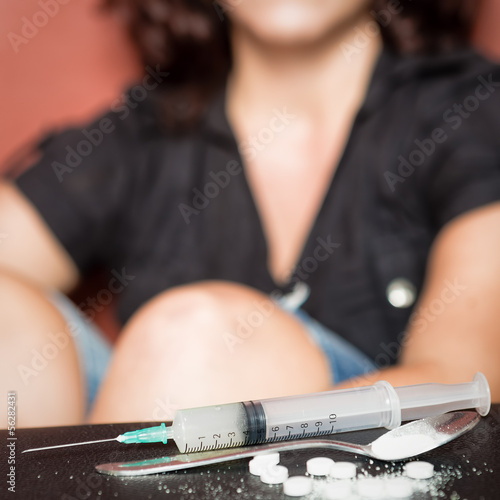 Photo: Syringe and female drug addict sitting on the background Syringe and female drug addict sitting on the background