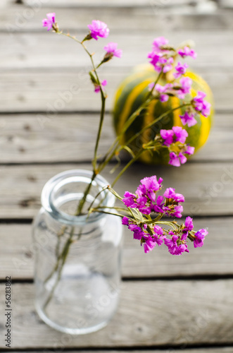 Photo: purple flowers in a glass bottle on the background of pumpkin purple flowers in a glass bottle on the background of pumpkin