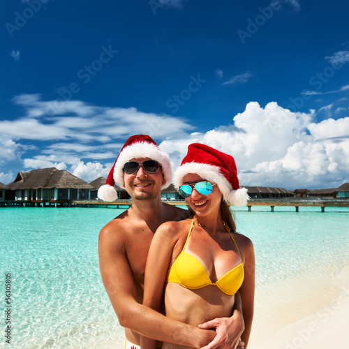 Photo: Couple in santa's hat on a beach at Maldives Couple in santa's hat on a beach at Maldives