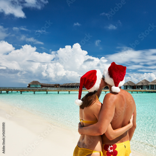 Photo: Couple in santa's hat on a beach at Maldives Couple in santa's hat on a beach at Maldives