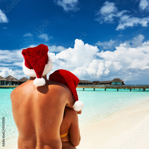 Photo: Couple in santa's hat on a beach at Maldives Couple in santa's hat on a beach at Maldives