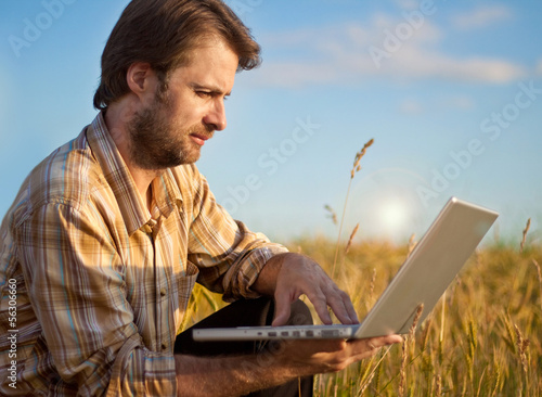 Photo: Modern farmer with laptop on his wheat field Modern farmer with laptop on his wheat field
