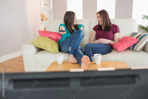 Photo: Two happy friends on the couch watching tv together Two happy friends on the couch watching tv together