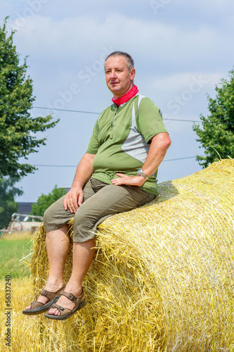 Photo: Farmer sitting on straw bales Farmer sitting on straw bales