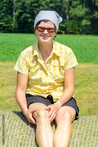 Photo: Peasant woman sitting on the hay bale Peasant woman sitting on the hay bale