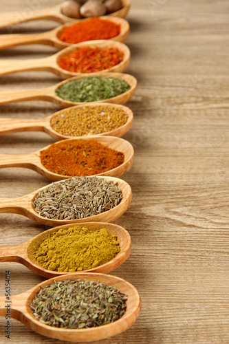 Photo: Assortment of spices in wooden spoons on wooden background Assortment of spices in wooden spoons on wooden background