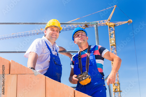 Photo: Construction site workers building house with crane Construction site workers building house with crane