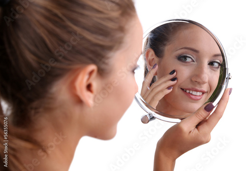 Photo: Beautiful girl preens before small mirror isolated on white Beautiful girl preens before small mirror isolated on white