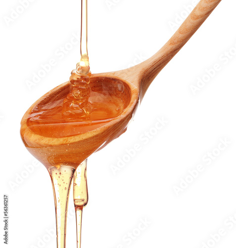 Photo: Honey dripping from a wooden honey dipper isolated on white back Honey dripping from a wooden honey dipper isolated on white back
