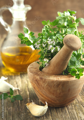 Photo: Oregano herb in wooden mortar and pestle. Oregano herb in wooden mortar and pestle.