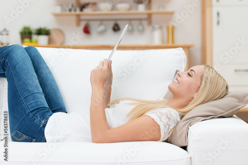 Photo: frau liegt auf dem sofa und liest ein ebook frau liegt auf dem sofa und liest ein ebook