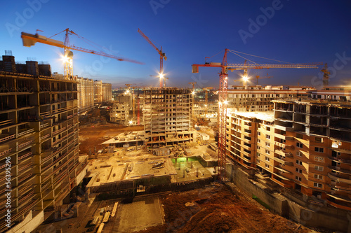 Photo: Lots of tower cranes build large residential buildings at night. Lots of tower cranes build large residential buildings at night.