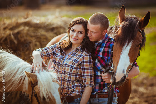 Photo: couple standing on farm with horses couple standing on farm with horses