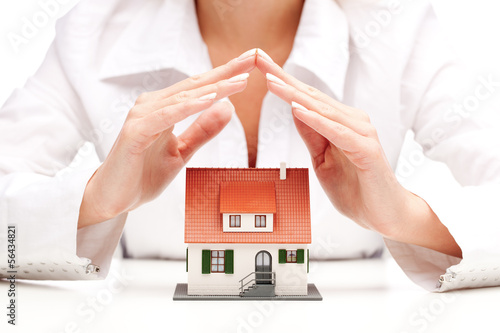 Photo: Female hands saving small house with a roof Female hands saving small house with a roof
