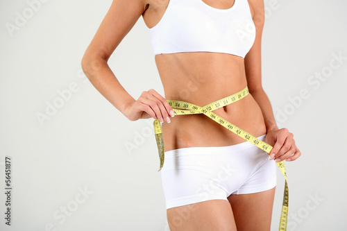 Photo: Slim girl with centimeter on gray background Slim girl with centimeter on gray background