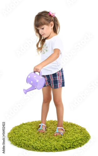 Photo: Little girl watering green grass isolated on white Little girl watering green grass isolated on white