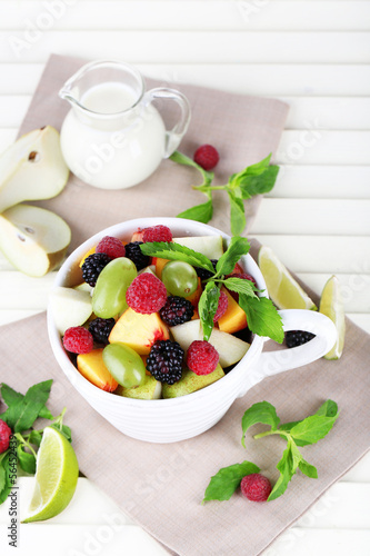 Photo: Fruit salad in cup on wooden table Fruit salad in cup on wooden table