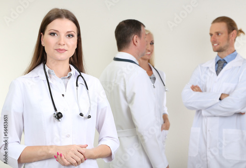 Photo: Doctor standing in front of coworkers on grey background Doctor standing in front of coworkers on grey background