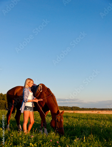 Photo: Young girl walking with a horse in the field Young girl walking with a horse in the field