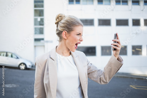 Photo: Angry stylish businesswoman shouting at her phone Angry stylish businesswoman shouting at her phone