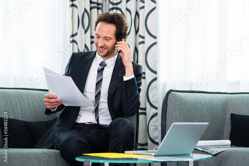 Photo: businessman in business hotel is on the phone businessman in business hotel is on the phone