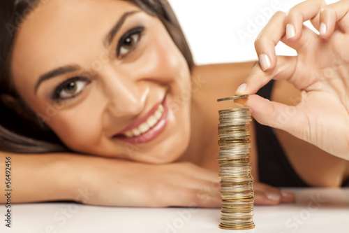 Photo: happy attractive girl arrange the coins in column happy attractive girl arrange the coins in column