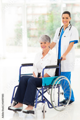 Photo: young nurse pushing middle aged patient on wheelchair young nurse pushing middle aged patient on wheelchair