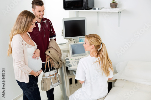 Photo: Female Gynecologist Looking At Expectant Couple Female Gynecologist Looking At Expectant Couple