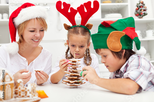 Photo: Happy family making a gingerbread cookie christmas tree Happy family making a gingerbread cookie christmas tree