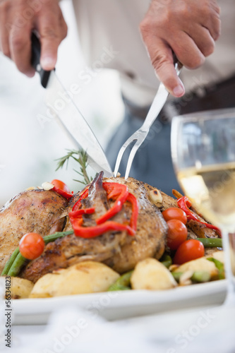Photo: Close up of a man carving the roast chicken Close up of a man carving the roast chicken